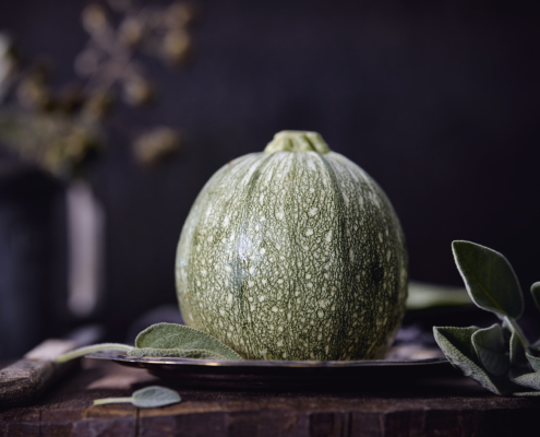 Runde Zucchini Foodfoto Runde Zucchini mit Salbei auf rustikalem Holztisch