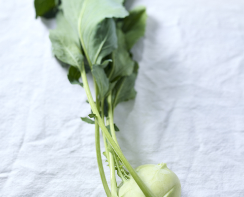Frischer Kohlrabi mit Blättern auf hellem Leinenstoff.