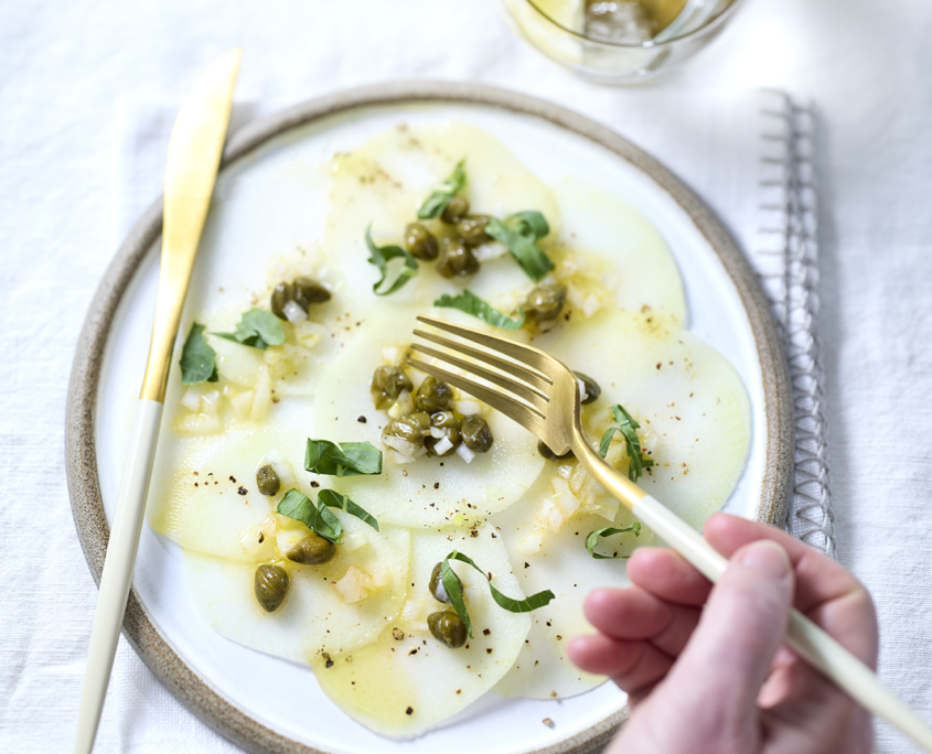 Dünn geschnittenes Kohlrabi-Carpaccio mit Kapern und Kräutern.