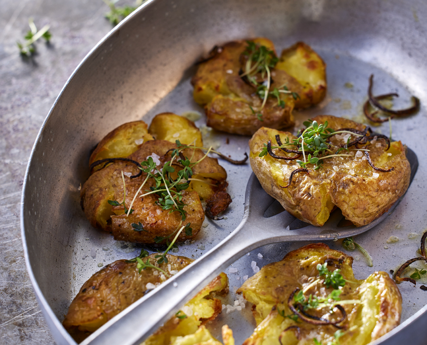 Detailaufnahme knuspriger Smashed Potatoes mit Harissa-Joghurt.