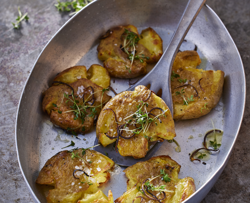Knusprige Smashed Potatoes mit Harissa-Joghurt und frischem Thymian.