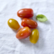 Gelbe und rote Kirschtomaten auf hellem Hintergrund.